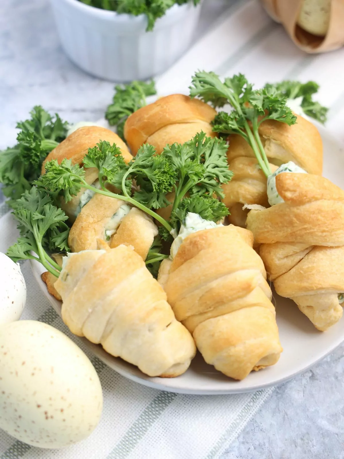 spinach dip inside baked crescent rolls shaped like carrots on plate.