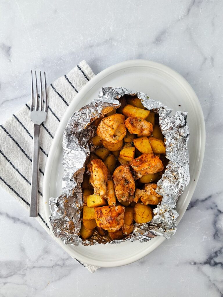 air fryer chicken and potatoes bundle on white plate with fork.