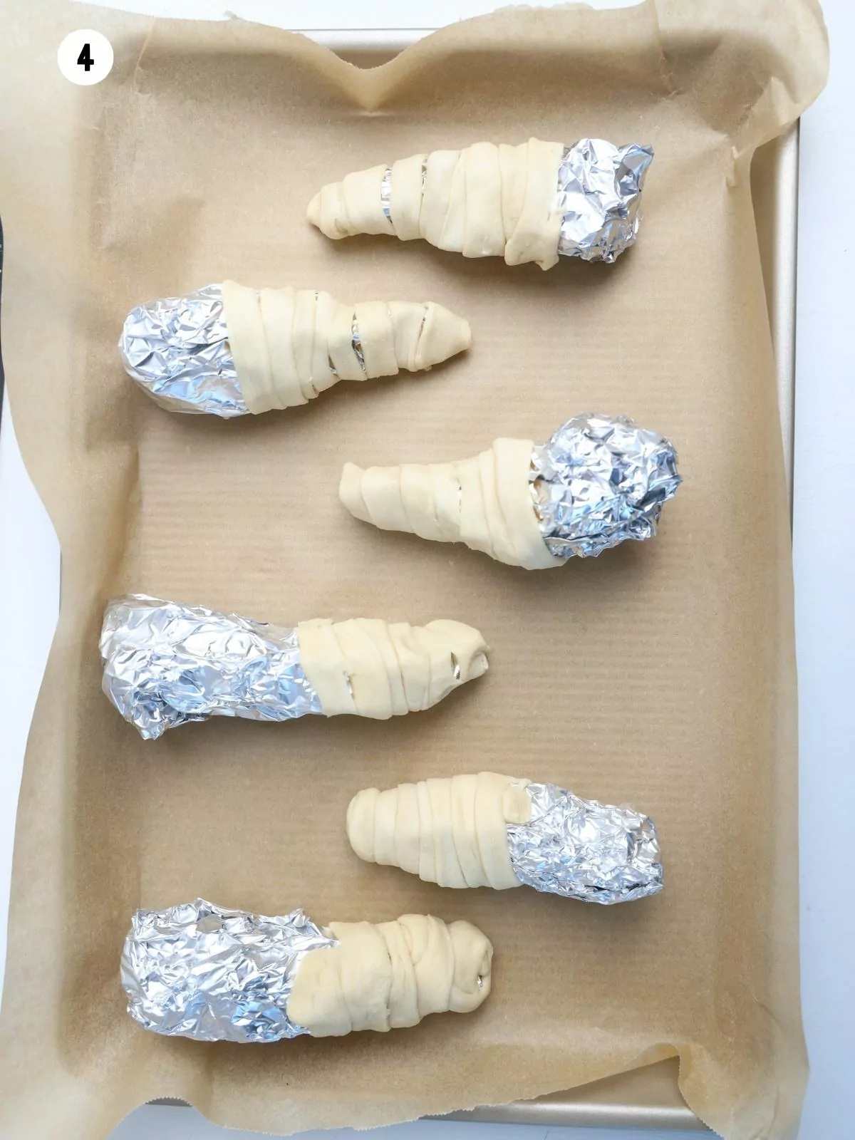 crescent roll dough strips wrapped around aluminum foil.