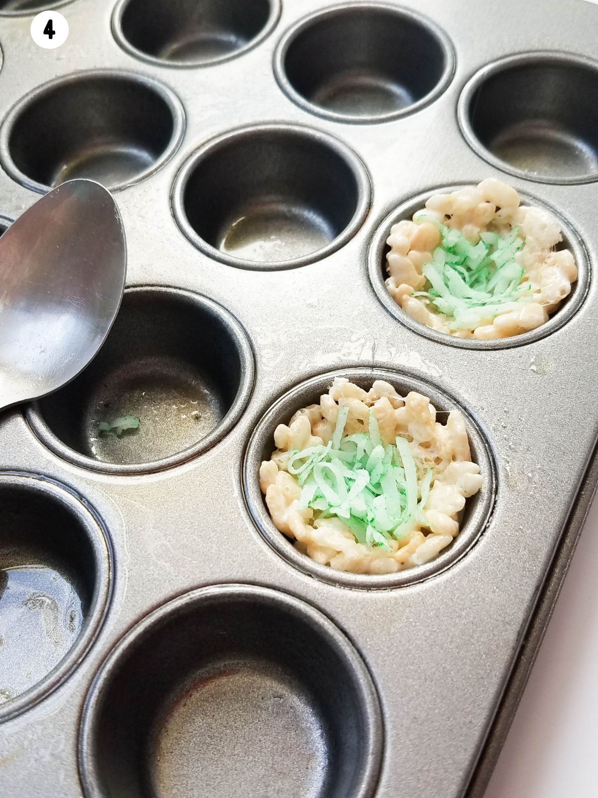 adding green colored coconut to the top of marshmallow nests in muffin pan.