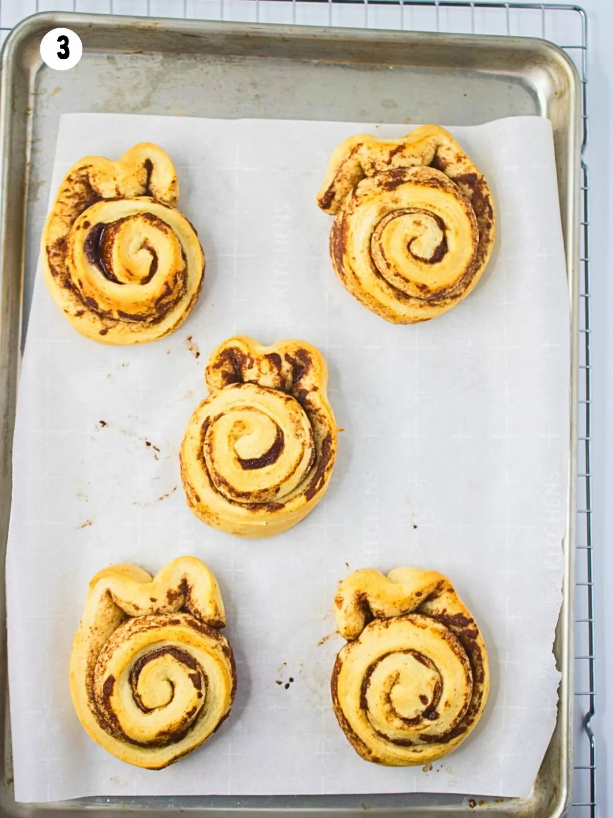 baked cinnamon rolls on tray with parchment paper.