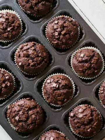 Soft and fluffy chocolate muffins cooling in a muffin pan.