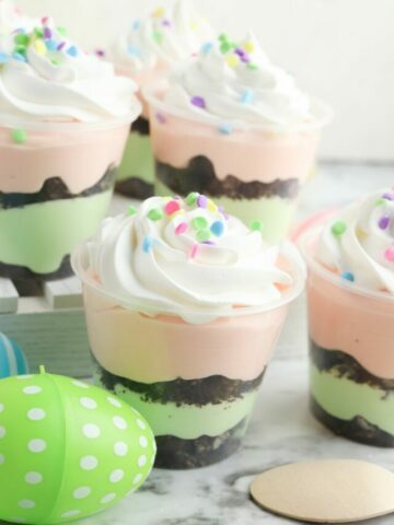 pink and green pudding layered with crushed oreos in clear cups