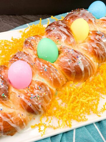 bread studded with colored eggs on white tray.