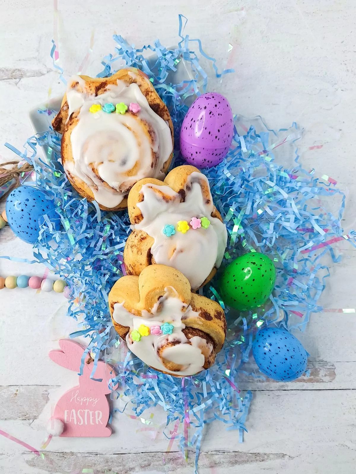 decorated cinnamon rolls with frosting and flower shaped sprinkles.