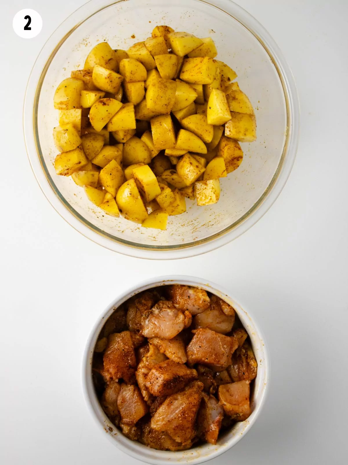 seasoned chicken and potatoes in bowls.