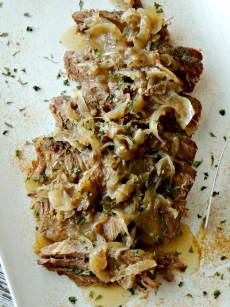Sliced London broil with caramelized onions on a white plate.