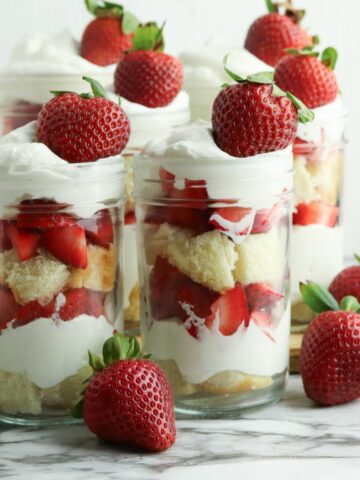 Mason jar filled with layers of pound cake, strawberries, and homemade whipped cream.