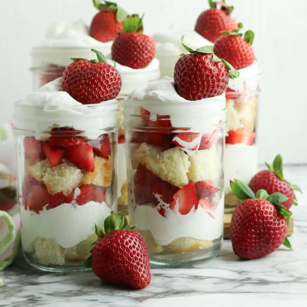Mason jar filled with layers of pound cake, strawberries, and homemade whipped cream.