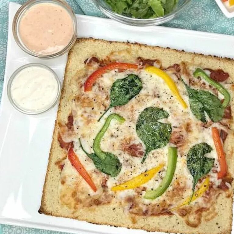 low carb pizza with peppers, spinach and cheese on white plate.