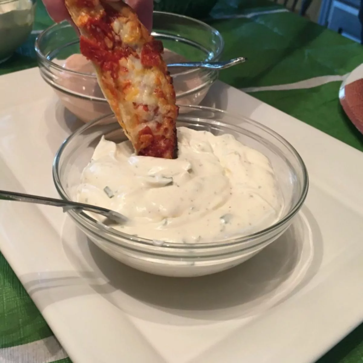 Piece of pizza dipping into ranch dressing.