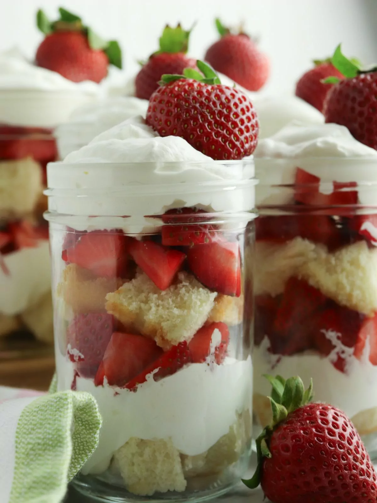 closeup of a jar with cake, whipped cream and strawberries.