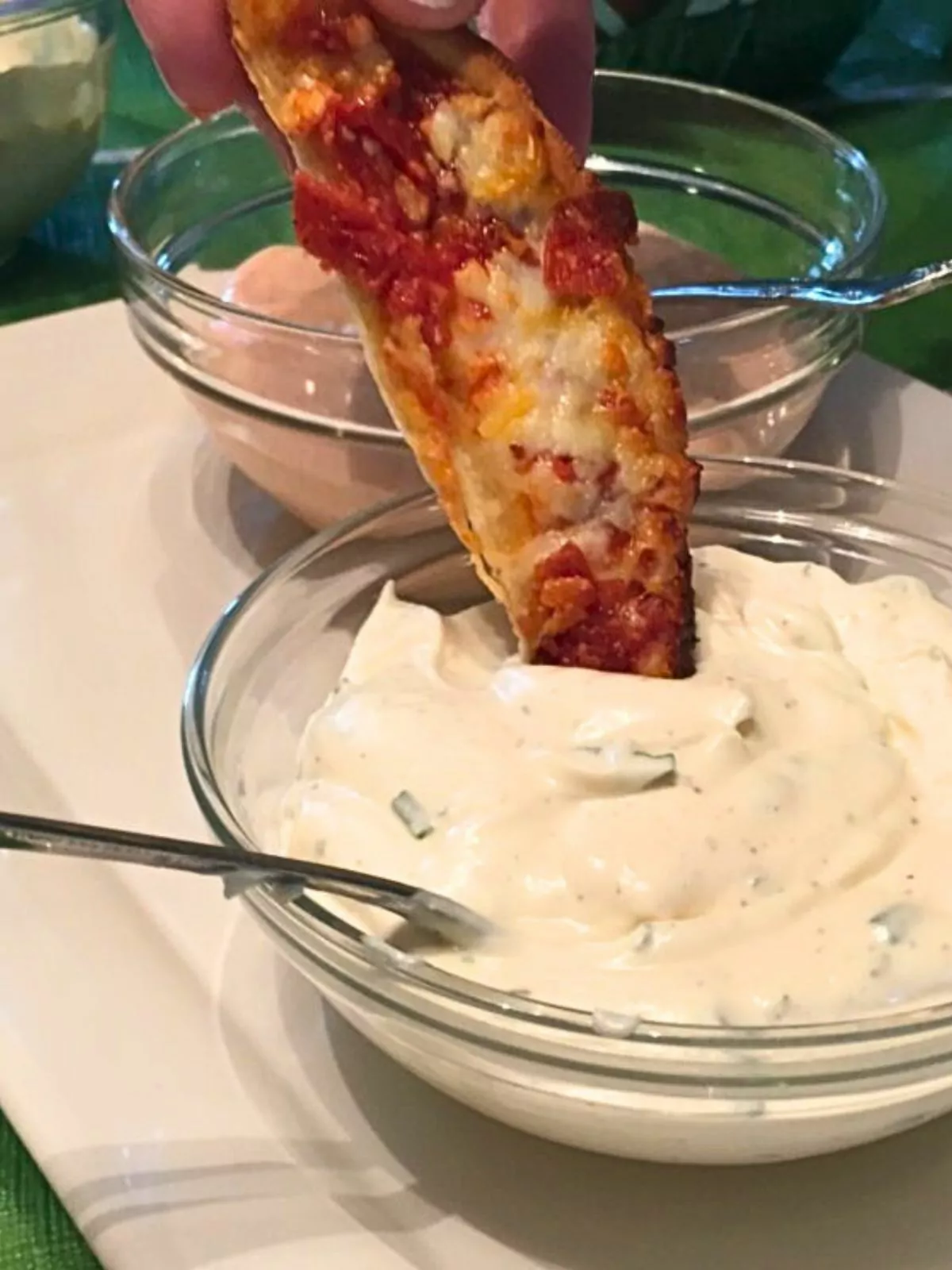 closeup of pizza dipping into a bowl of dip.