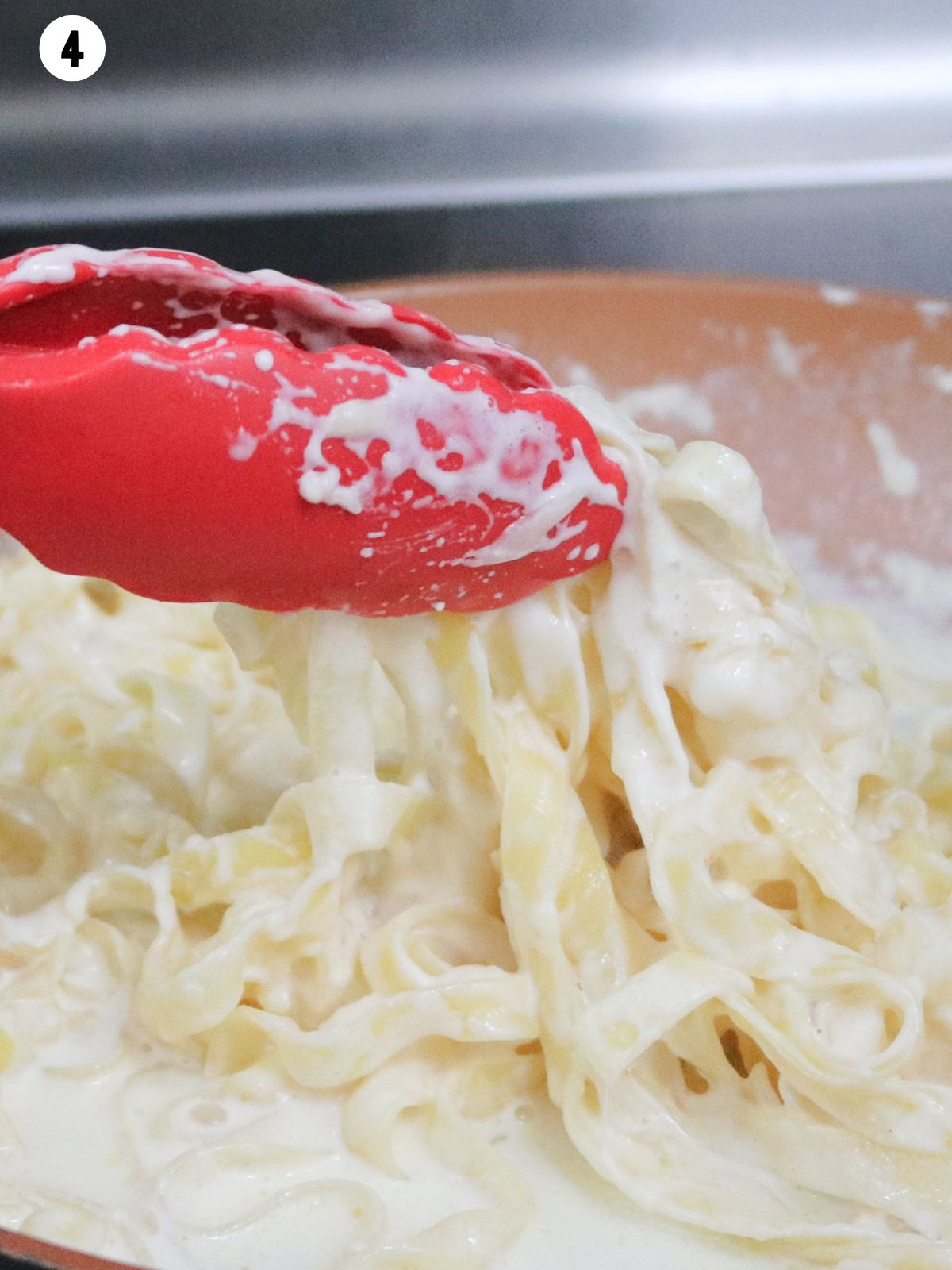 tossing pasta in alfredo sauce.