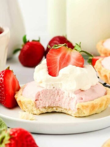 Several small tartlets filled with pink mousse and topped with sliced strawberries.