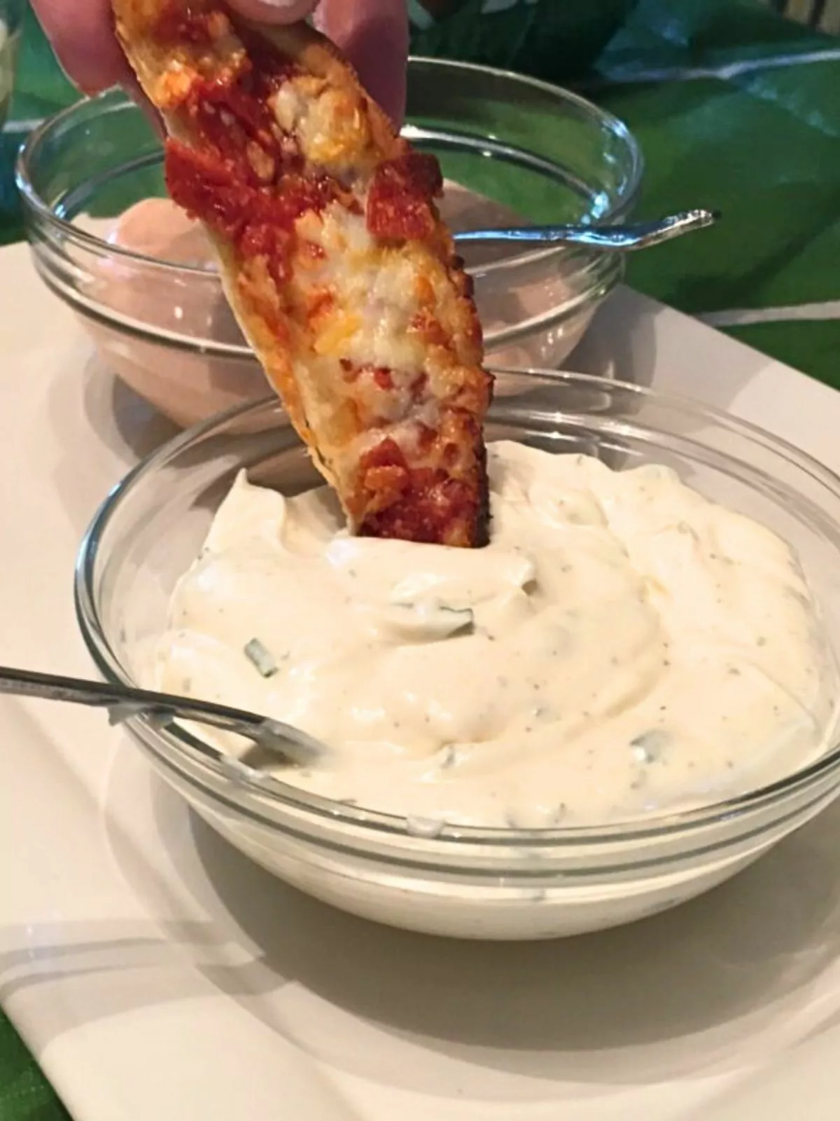 slice of pizza dipping into bowl of ranch dip.