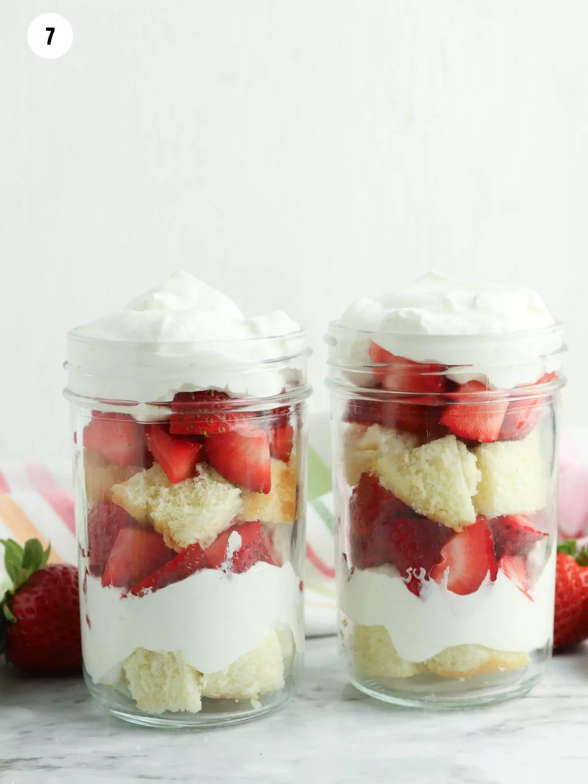 whipped cream and pound cake in jars with strawberries.