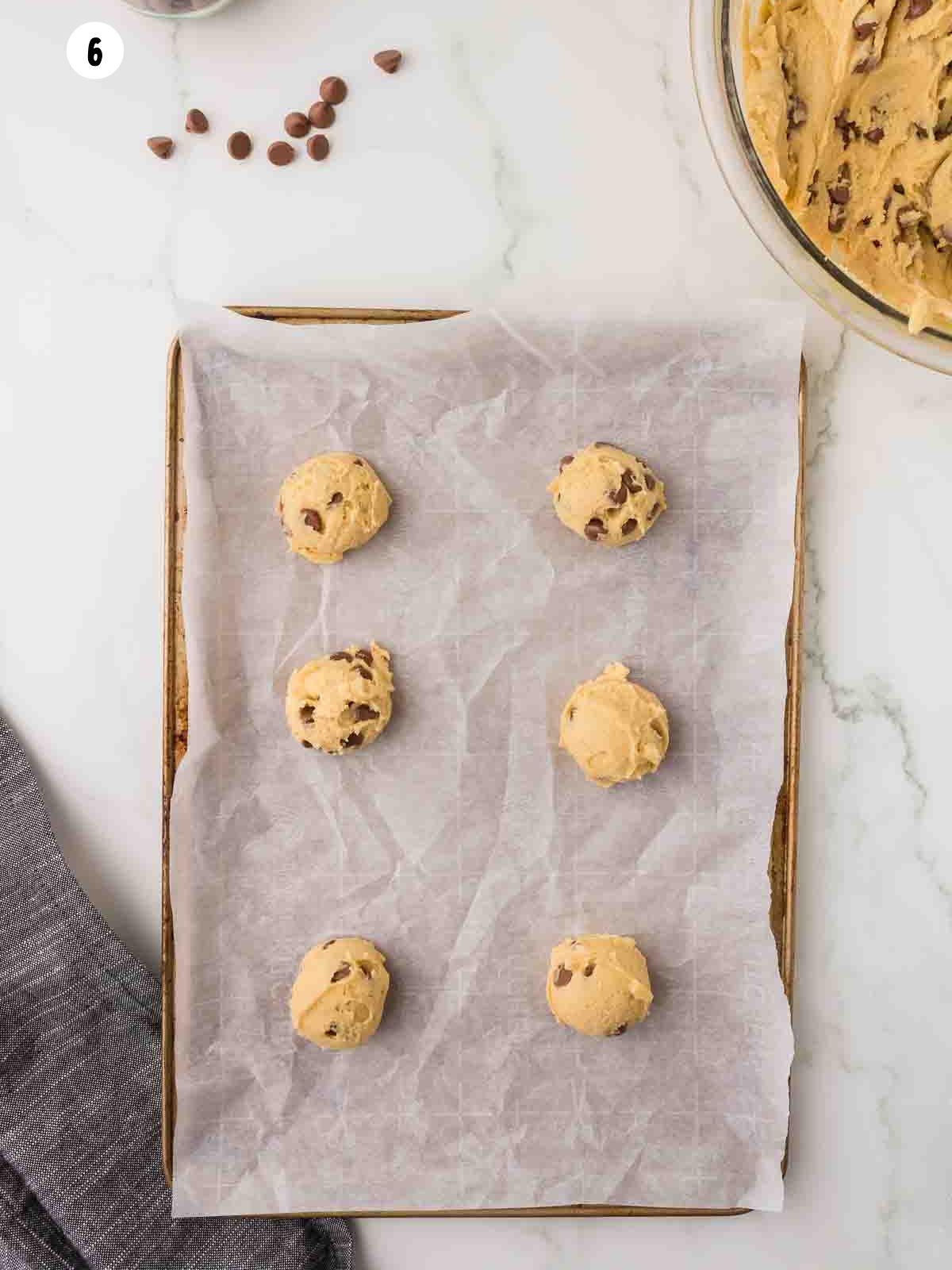 scoops of cookie dough on a parchment lined baking sheet