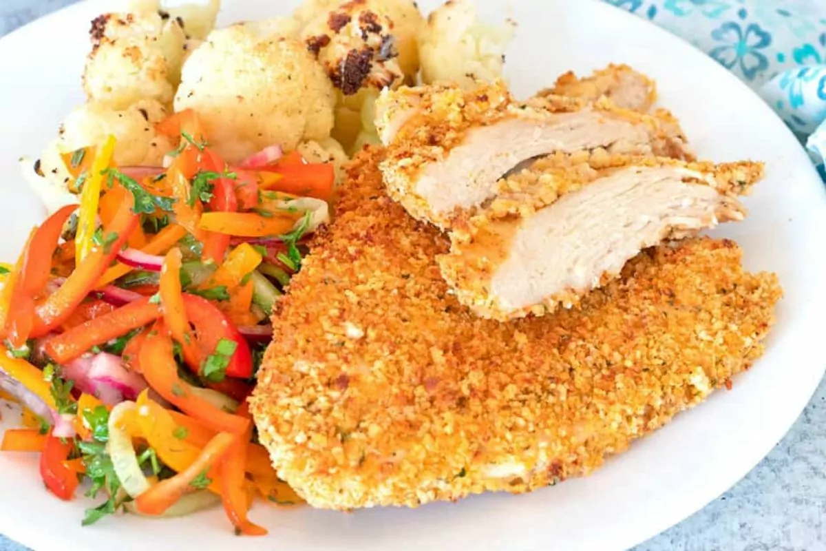 crispy chicken cutlet on plate with vegetable medley.