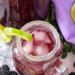 mason jar glass with mocktail and pitcher in background.