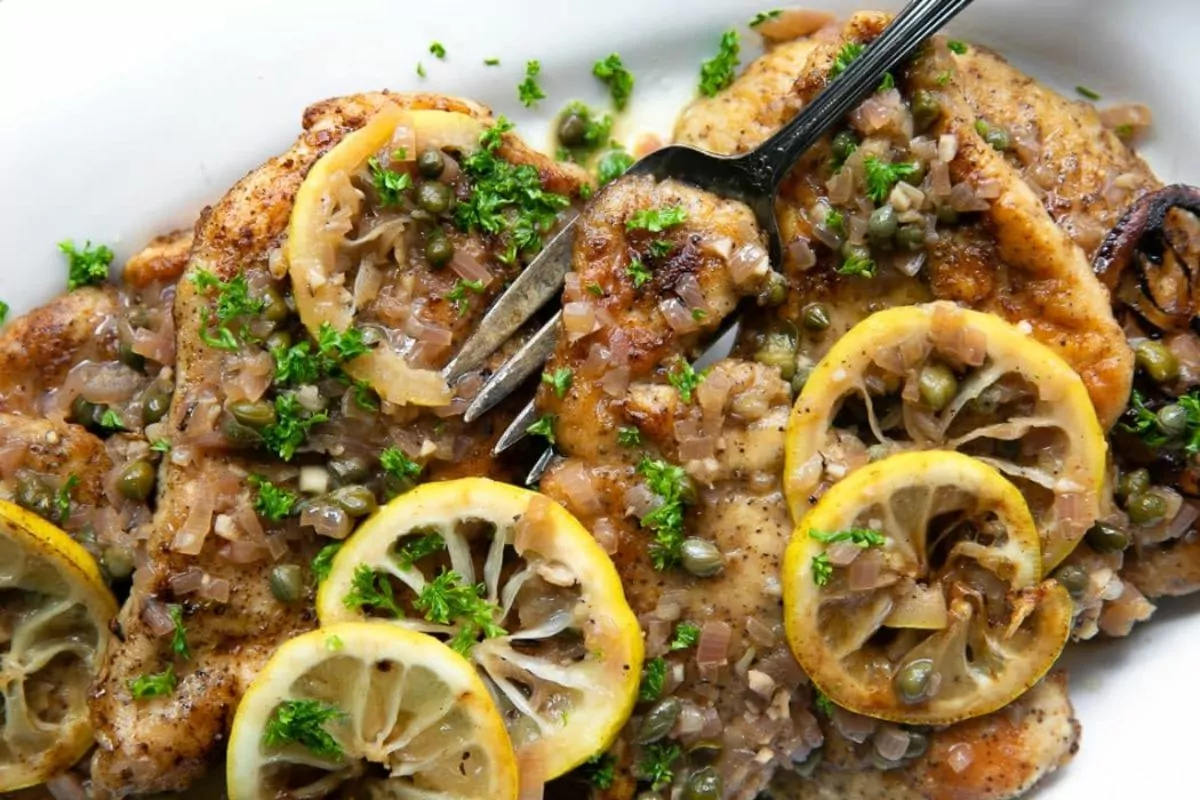plate of chicken piccata with lemon slices and capers.