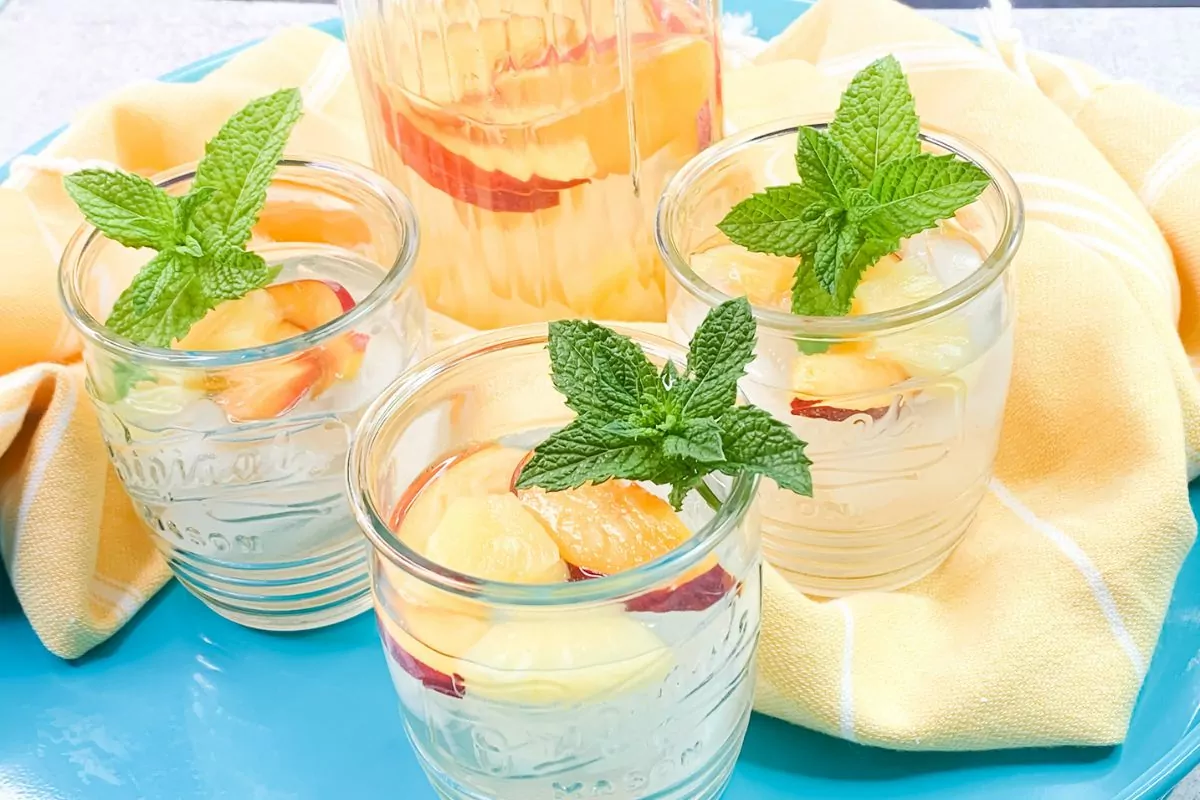 3 glasses of coconut water with peaches and fresh mint.