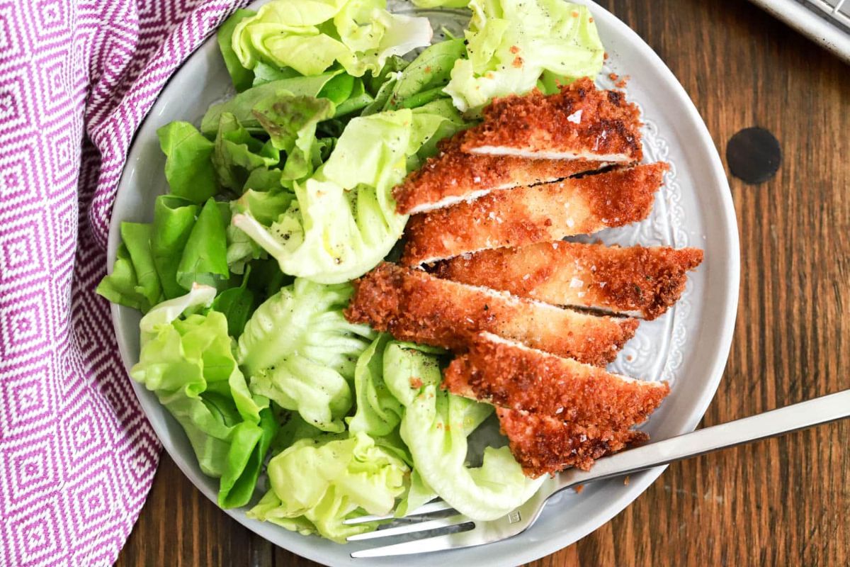 chicken on plate with salad and fork.