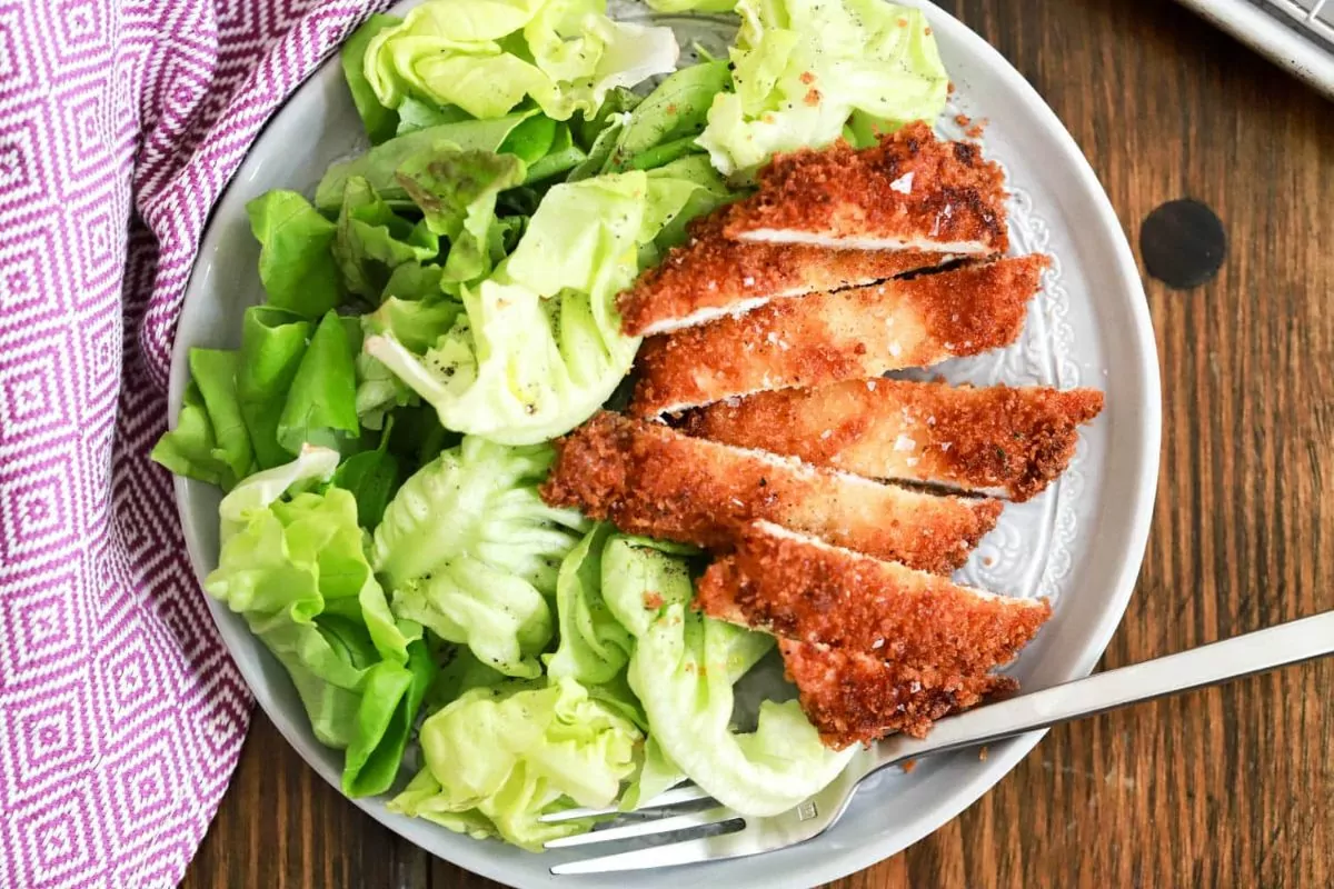 chicken on plate with salad and fork.
