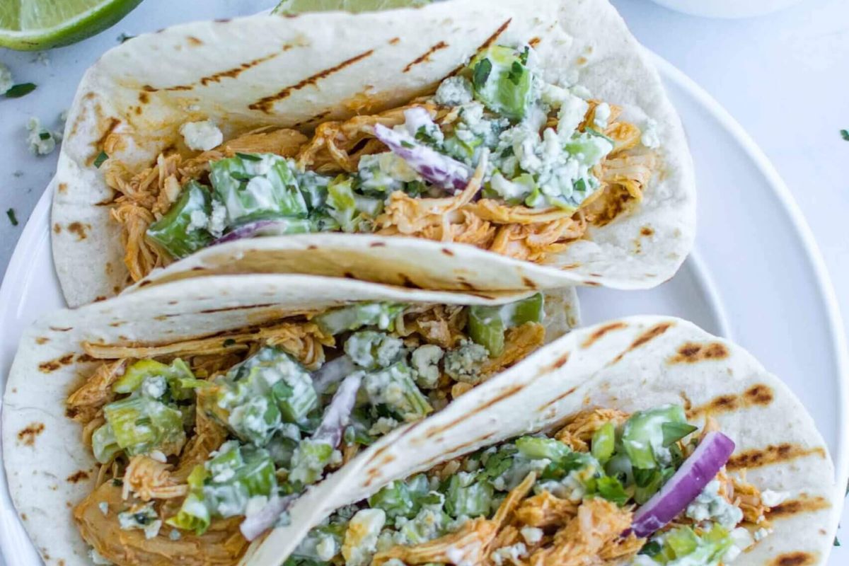 3 flour tortillas filled with shredded chicken, and taco toppings.
