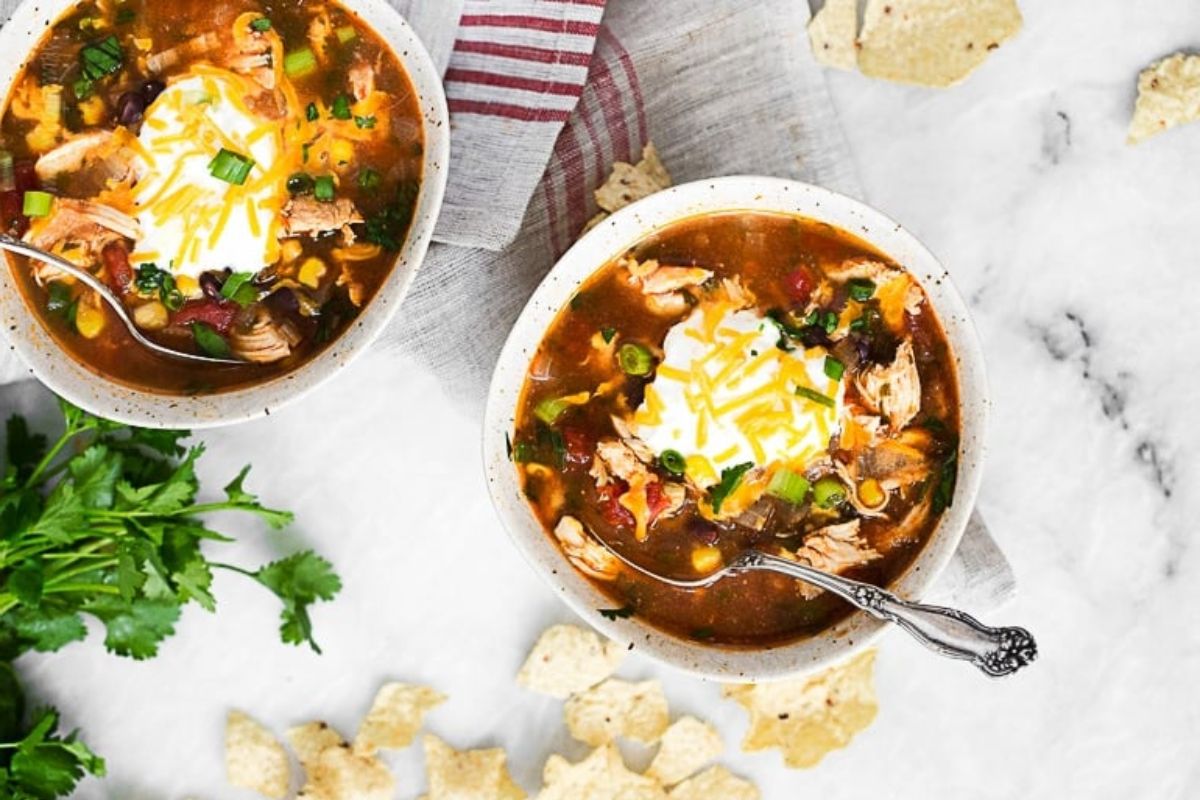 2 bowls of soup with spoons, topped with sour cream.