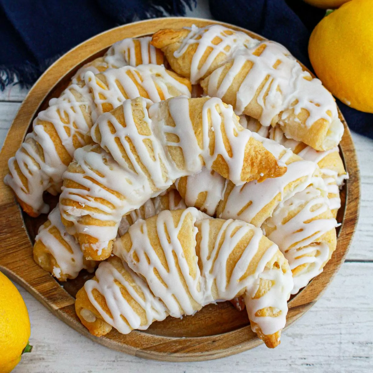 wooden plate filled with lemon crescent rolls and 2 lemons on the side.