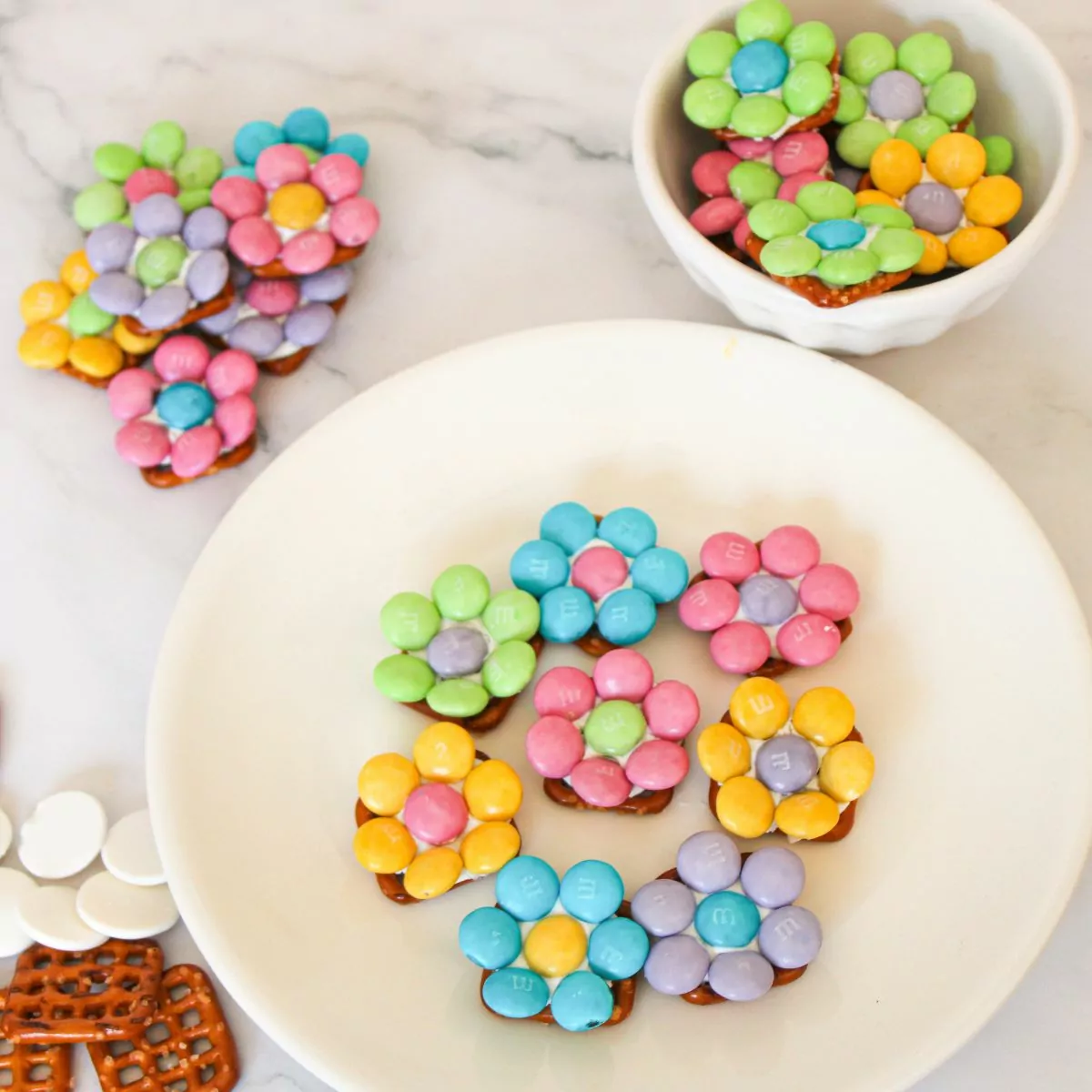 pastel M&M candies on top of waffle shaped pretzels.