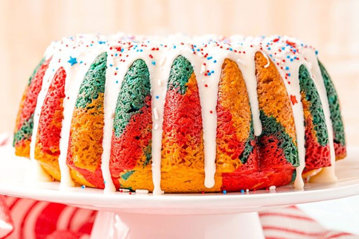 A red, white, and blue marble Bundt cake on a cake stand, ready to be enjoyed.
