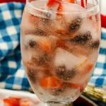 glass filled with water and fruit infused ice cubes.