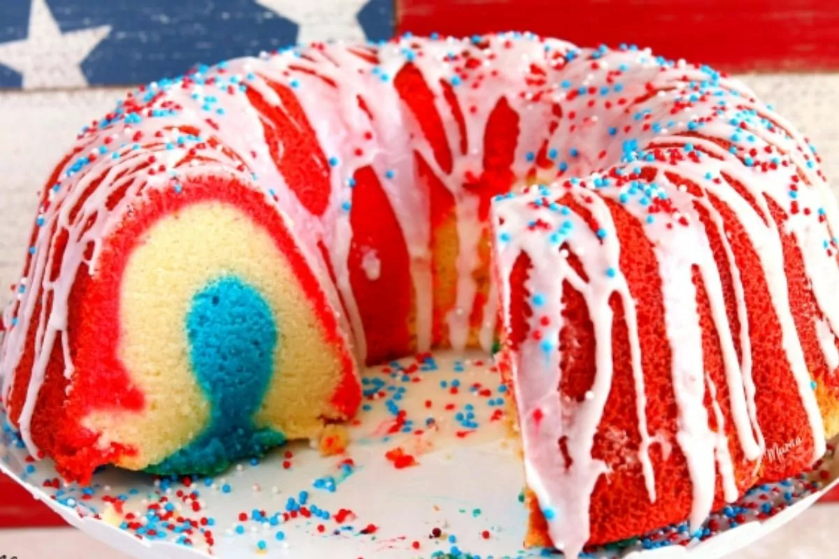 cake sliced to show the patriotic marbled effect with icing and sprinkles.