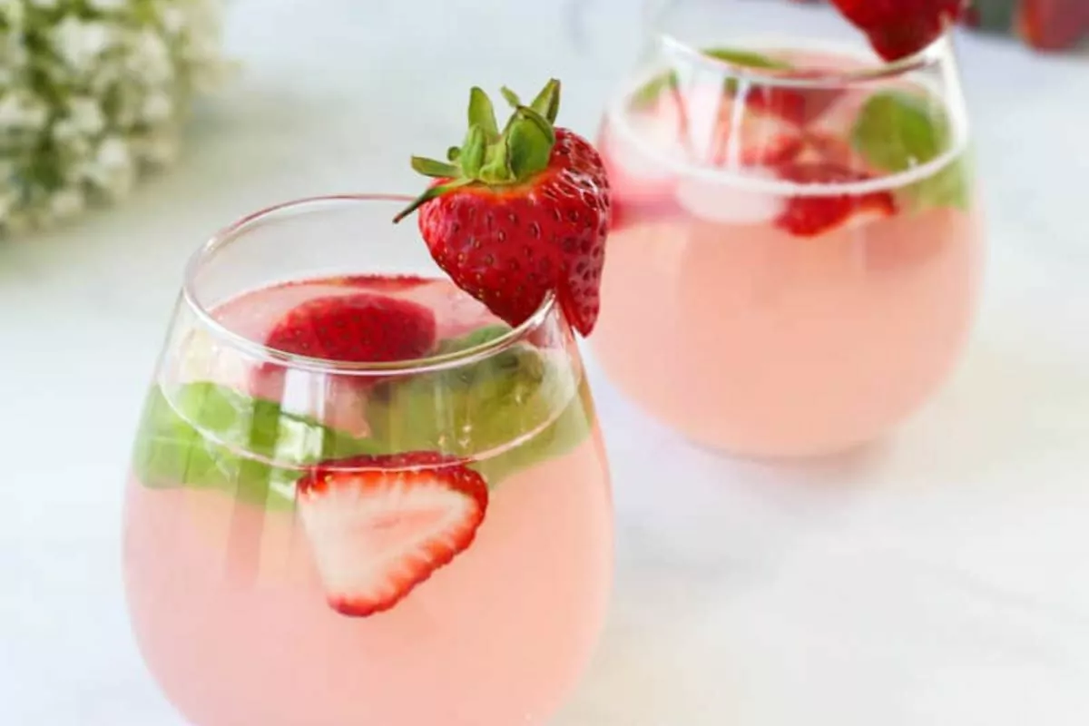 pink colored beverage with fresh strawberries in 2 glasses.