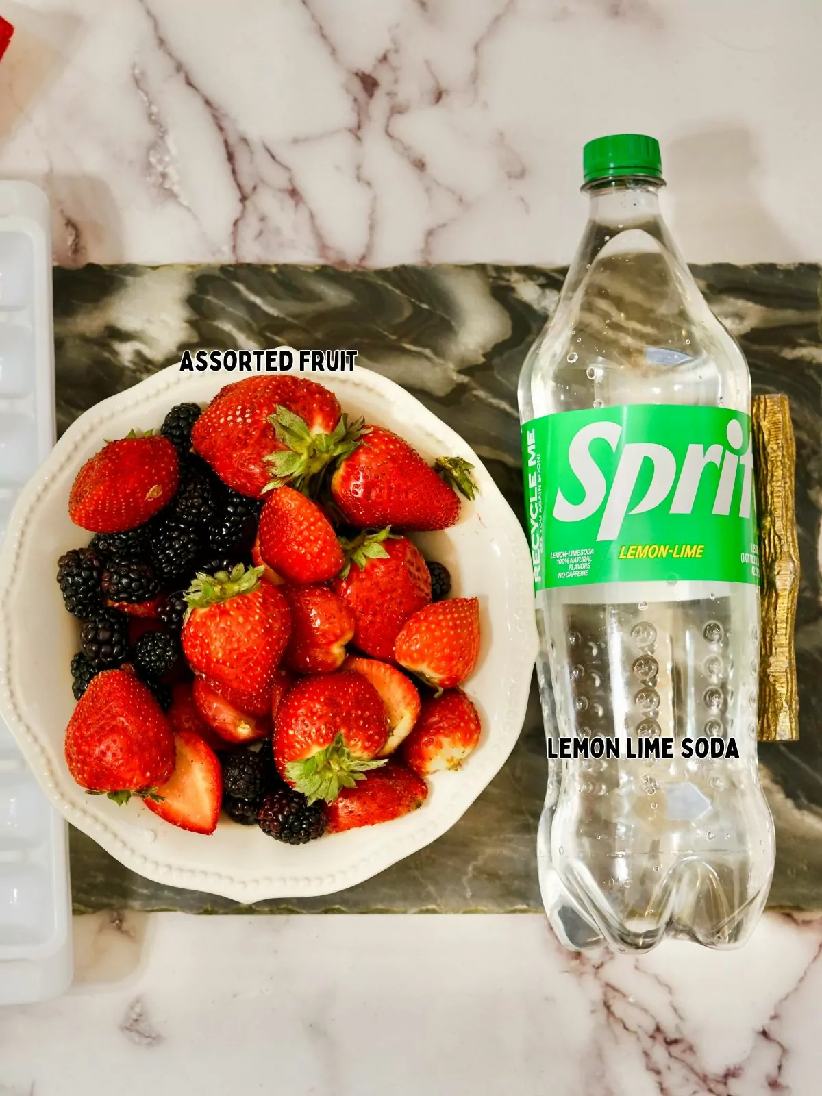 bowl of strawberries and blackberries and a bottle of lemon lime soda.