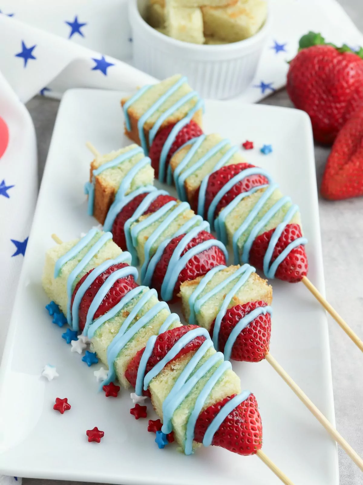 Patriotic fruit kabobs with strawberries, pound cake cubes, and blue powdered sugar glaze.