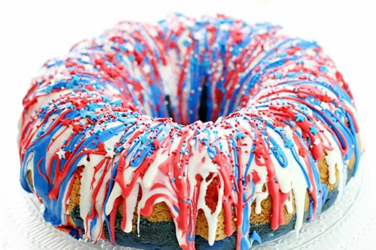 Cake decorated with red, white and blue frosting dripping over the sides and sprinkles on top.