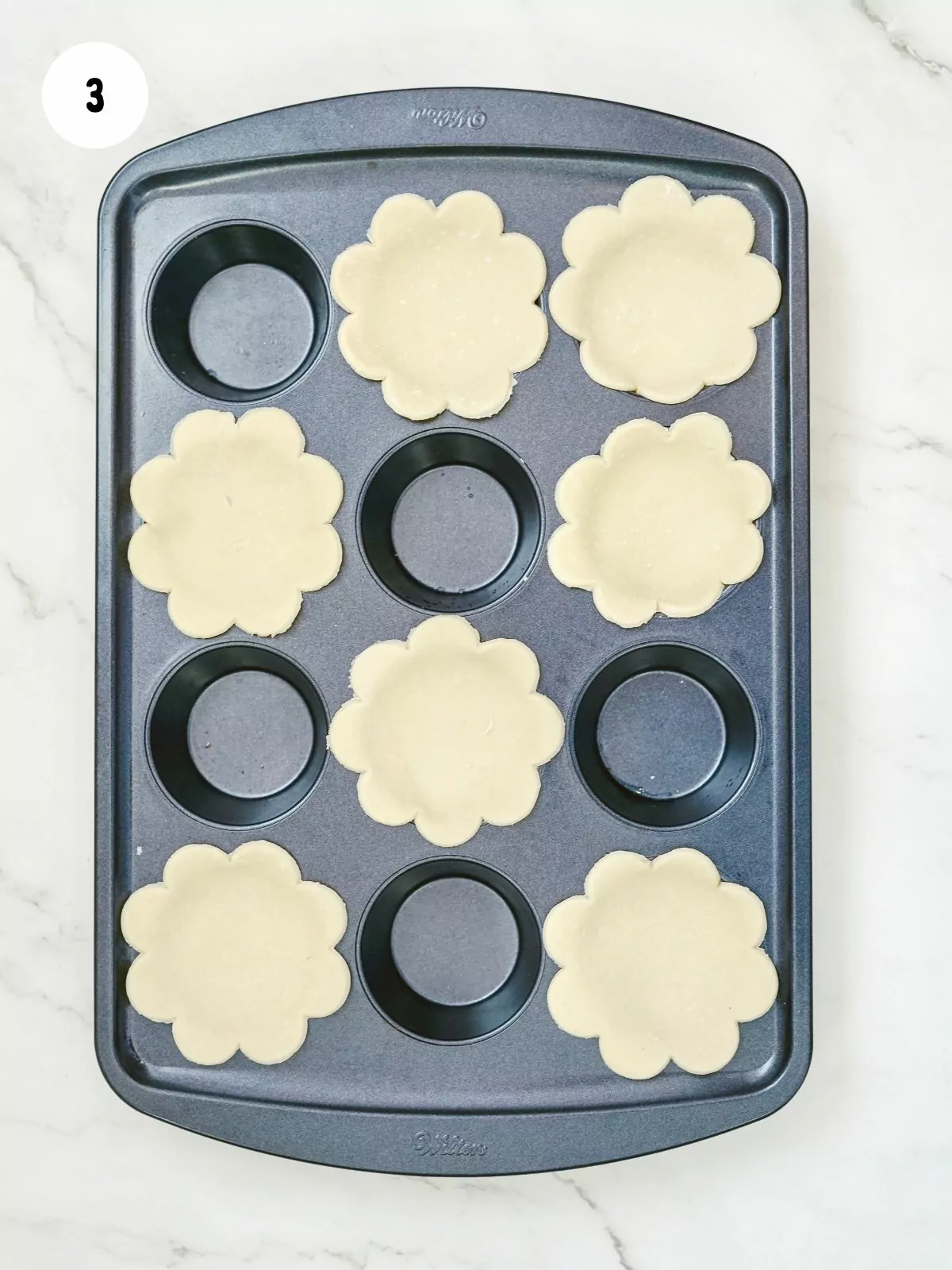 Press dough flowers into a muffin tin