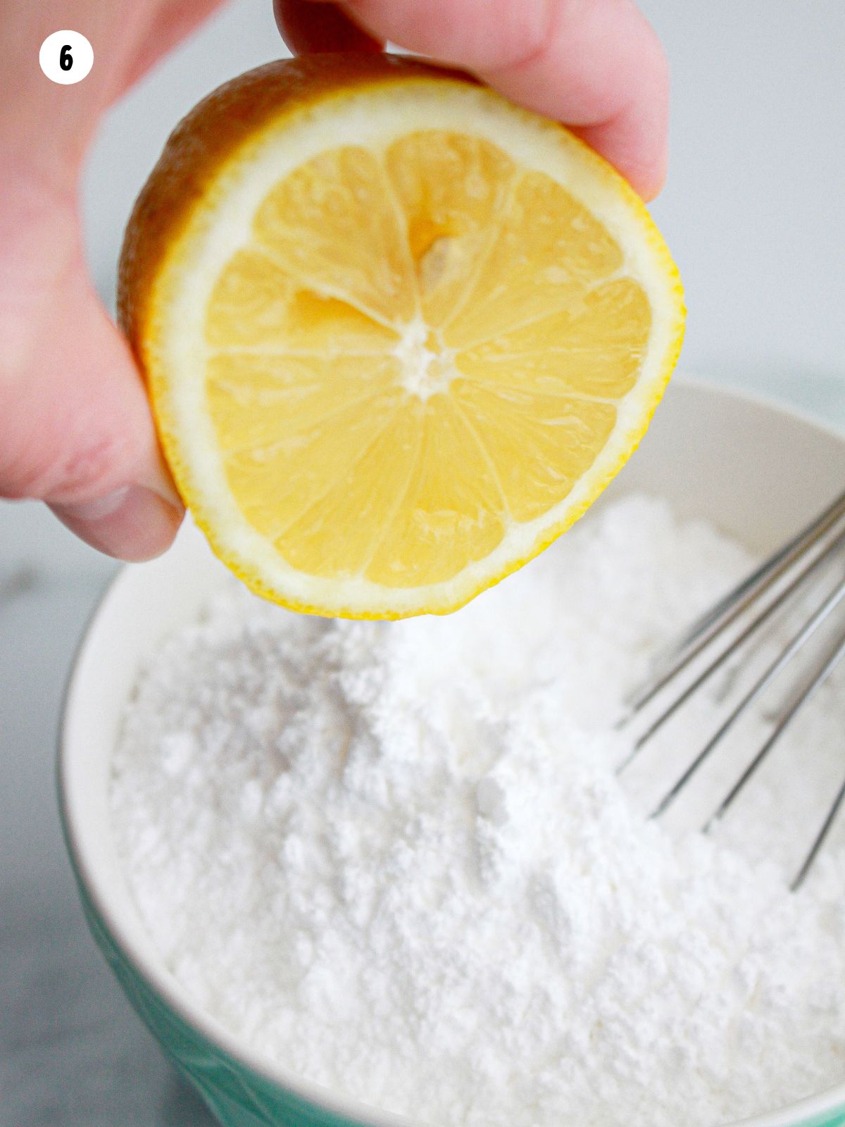 squeezing lemon juice in bowl of powdered sugar with whisk.