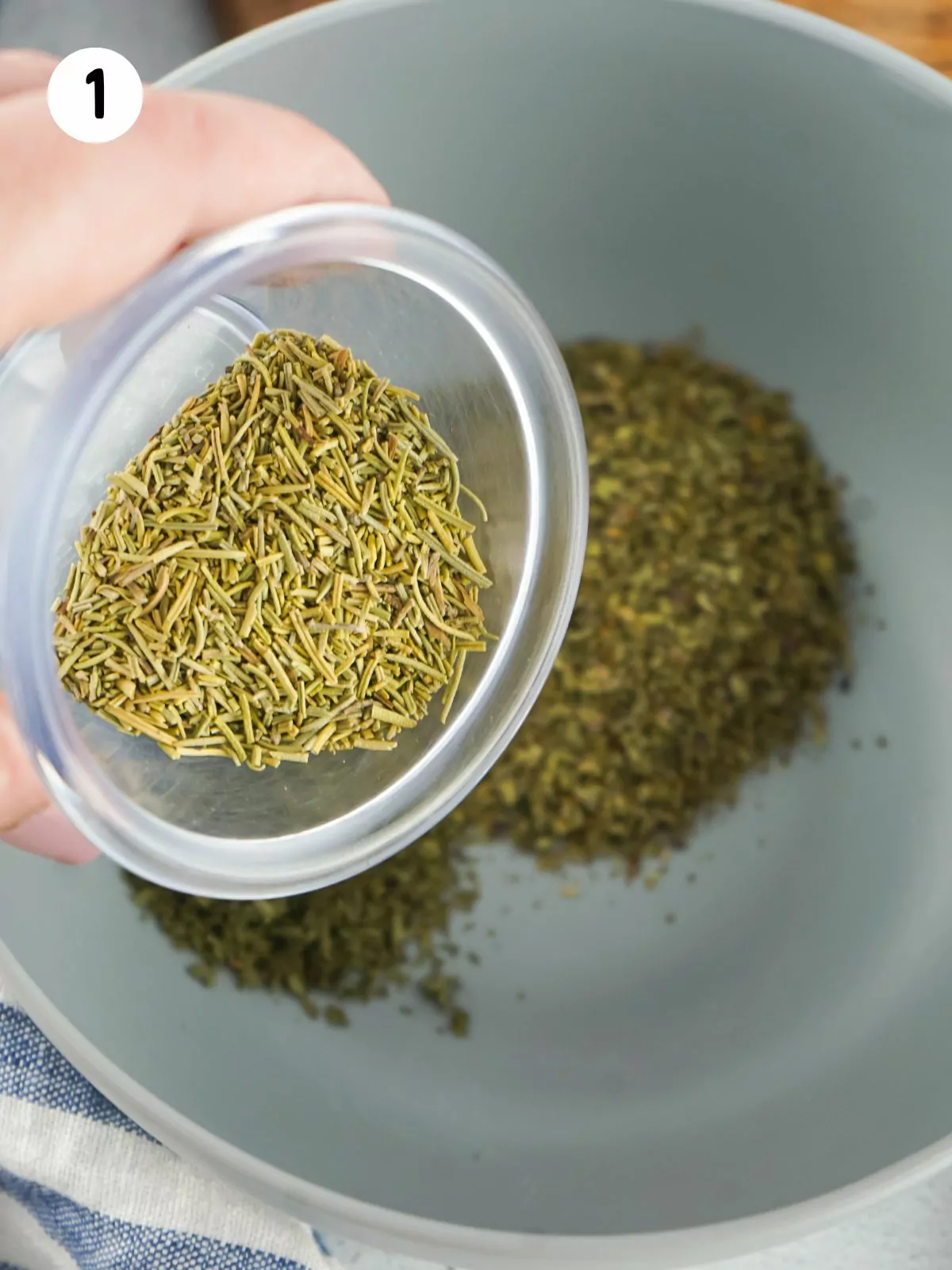 dried rosemary in plastic container over small bowl.