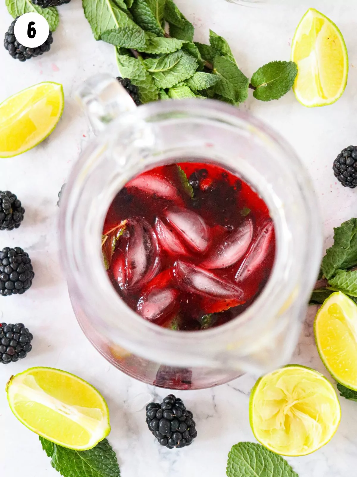 ice in pitcher with sparkling water, mint and blackberries with lime slices.