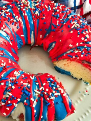 Festive 4th of July Bundt cake decorated with white frosting and patriotic sprinkles.
