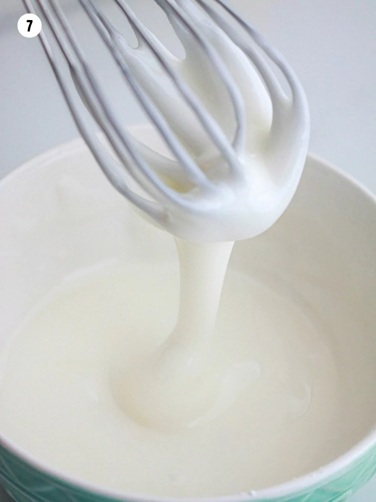 powdered sugar glaze in bowl with wire whisk.