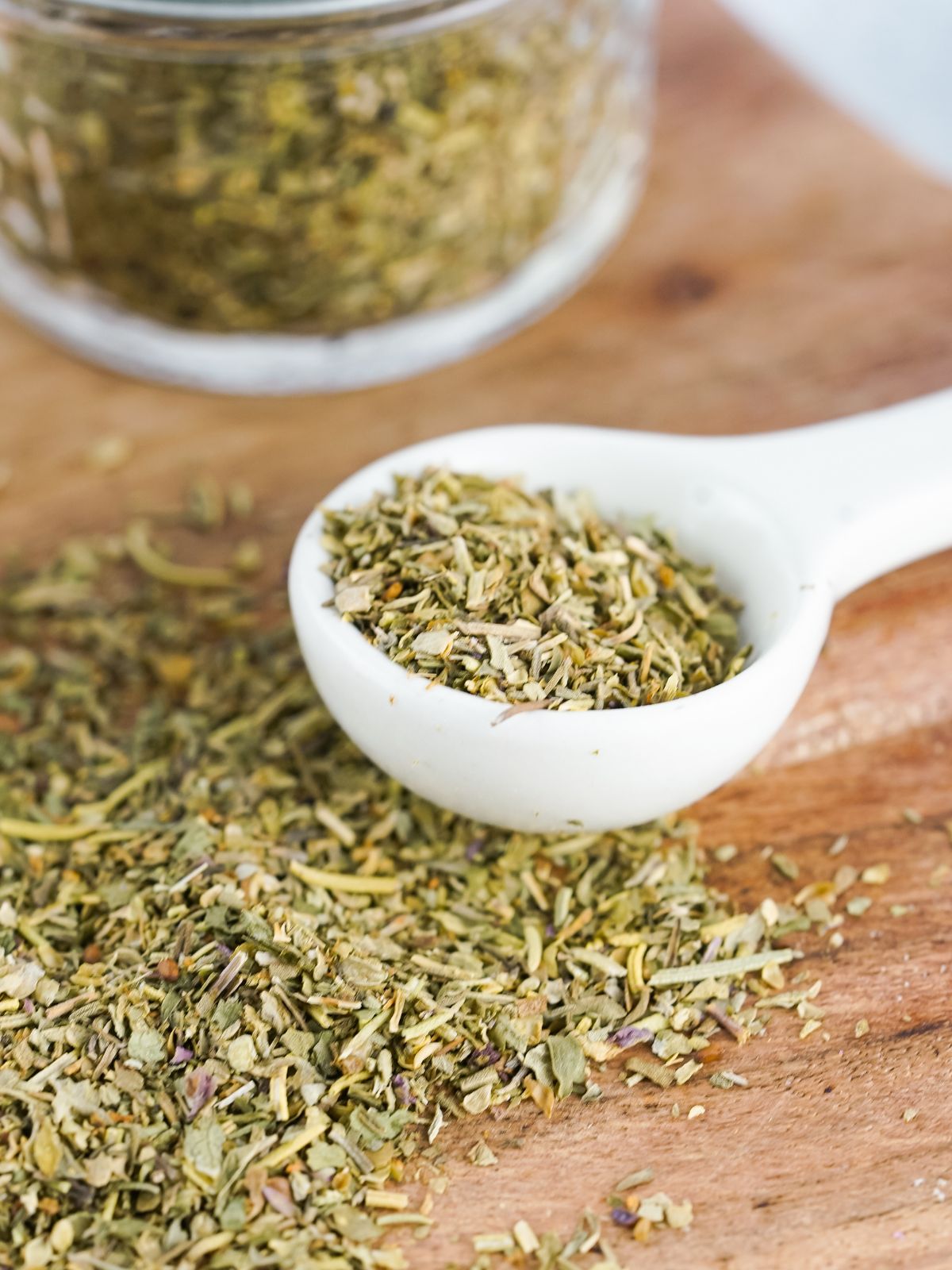 herbs on cutting board and in white tablespooon.