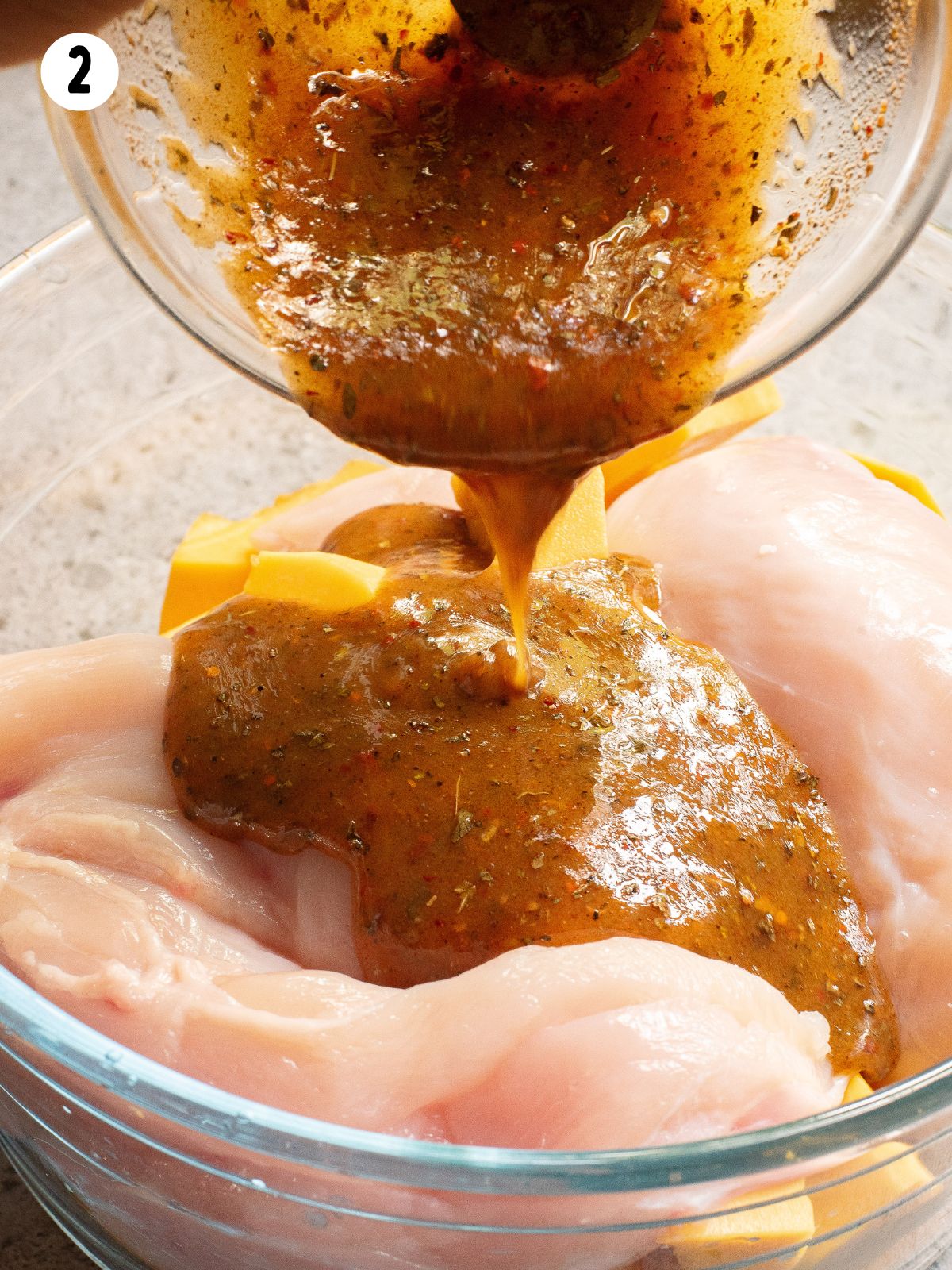 marinade being poured over chicken in bowl.