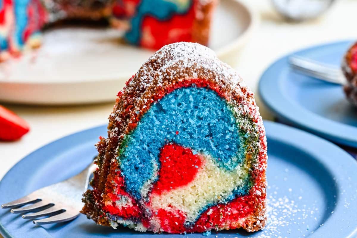 A slice of red, white, and blue Bundt cake on a plate with a fork, showcasing the festive marbled effect.