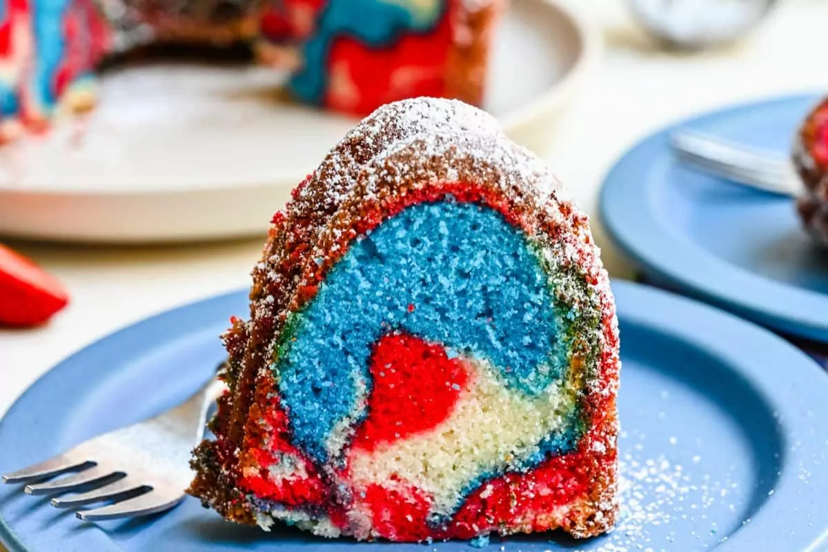 A slice of red, white, and blue Bundt cake on a plate with a fork, showcasing the festive marbled effect.