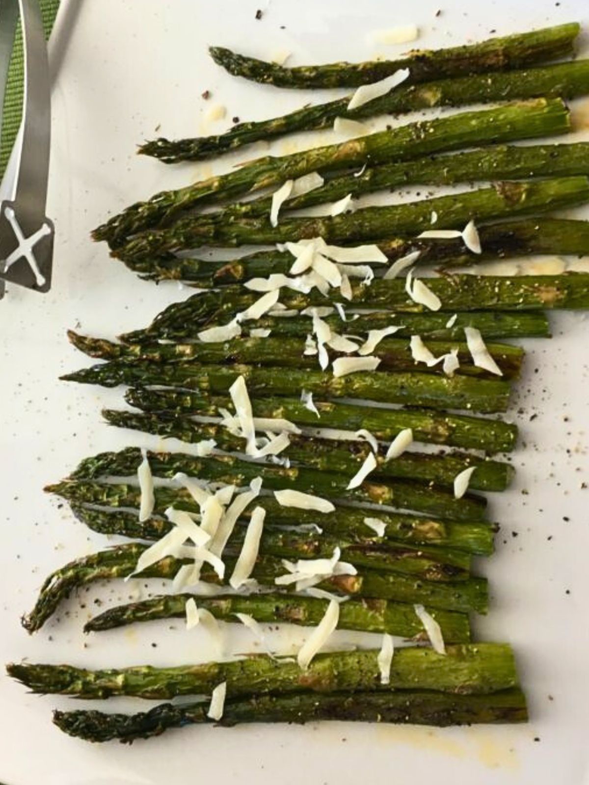 close up of roasted asparagus on white platter.